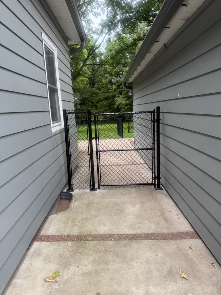 Black coated chain link gate installed between residential buildings