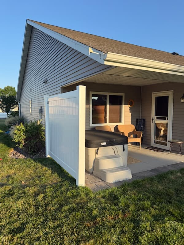 White vinyl privacy fence panel screening a patio hot tub area